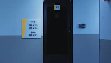 Un pasillo con señales direccionales que indican los números de habitación de 112 a 115, de 122 a 124 y de 116 a 121.