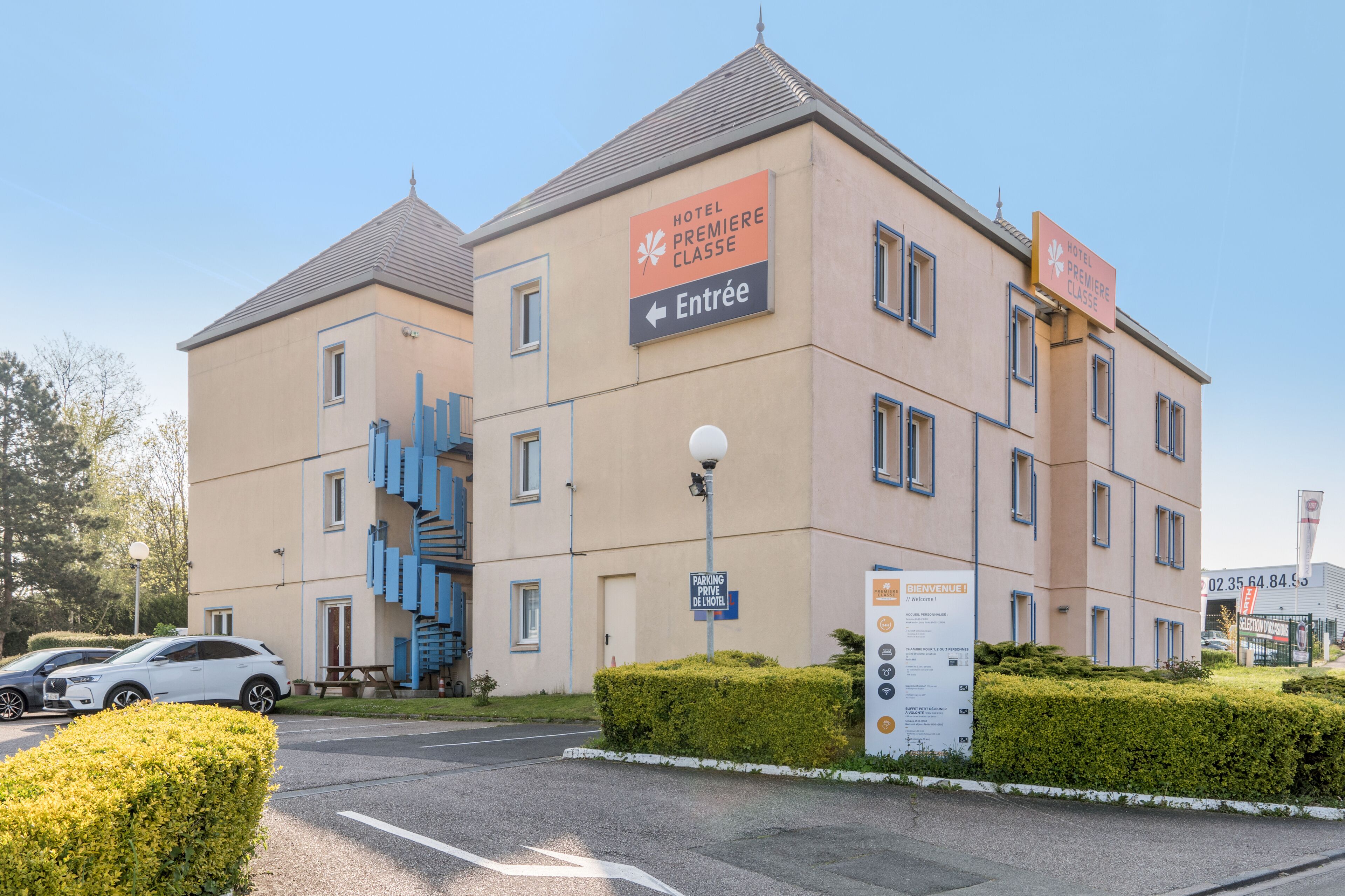 Hotellirakennus, jossa on kyltti, joka osoittaa sisäänkäynnin, sekä pysäköintikyltti.