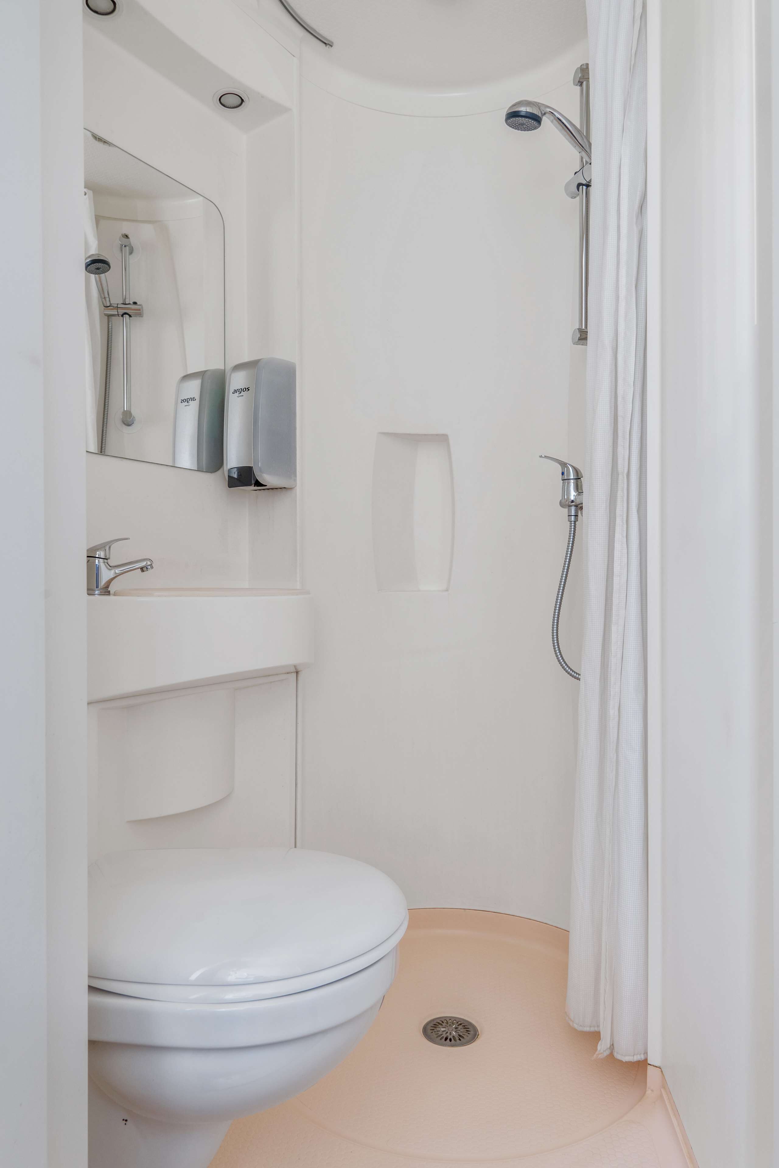 A small, modern bathroom with a toilet, sink, and shower.