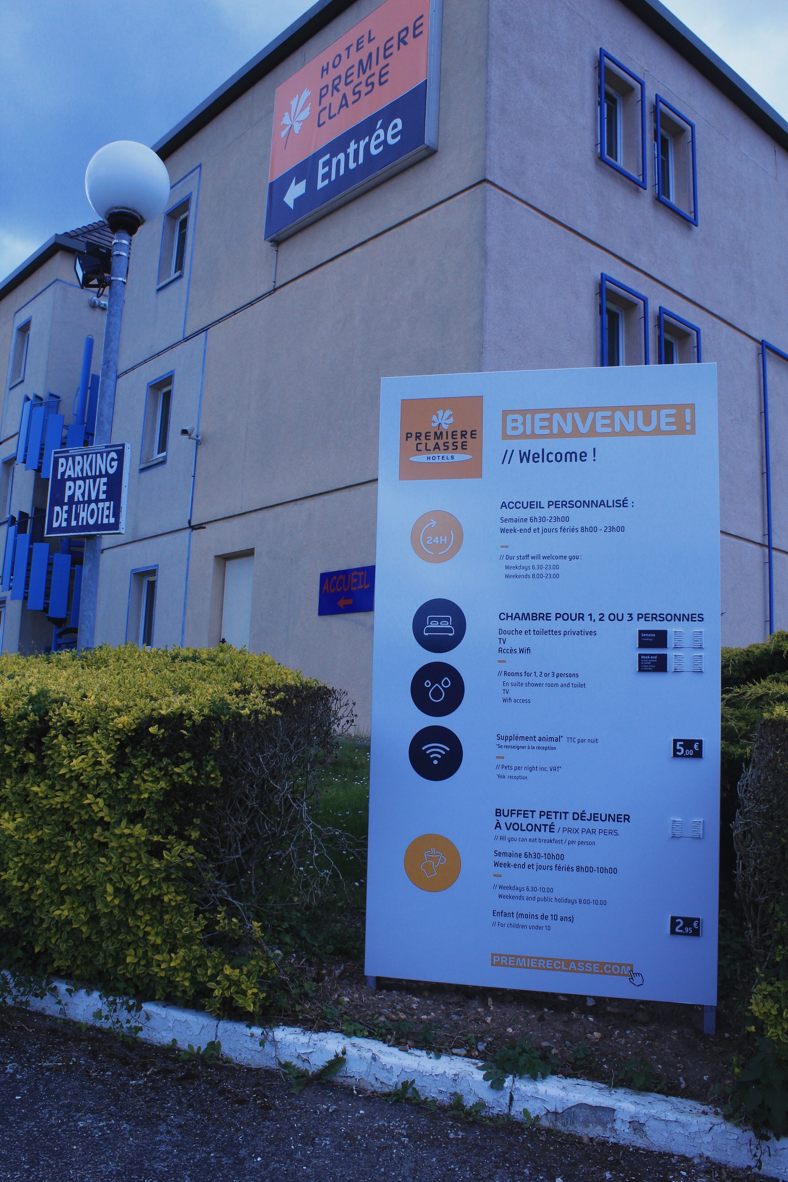 A hotel entrance sign with directions, parking information, and welcome details including personalized check-in hours and room types.