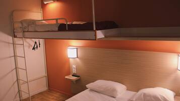 Une chambre avec un lit superposé, une échelle, une table de chevet avec une lampe et une étagère fixée au mur.