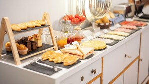 Un buffet con diversi cibi, tra cui panini, pasticcini e una selezione di formaggi.