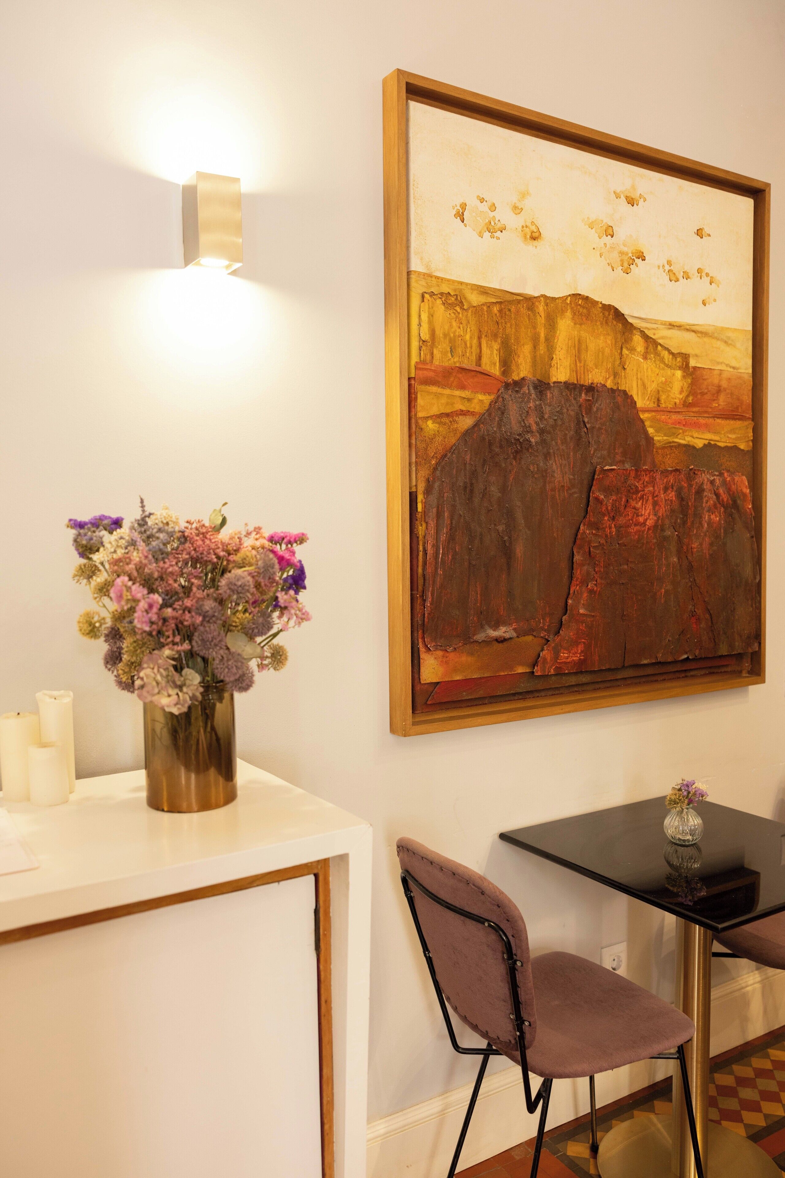 Ein Essbereich mit Tisch, Stühlen, einer Blumenvase und einem Bild an der Wand.