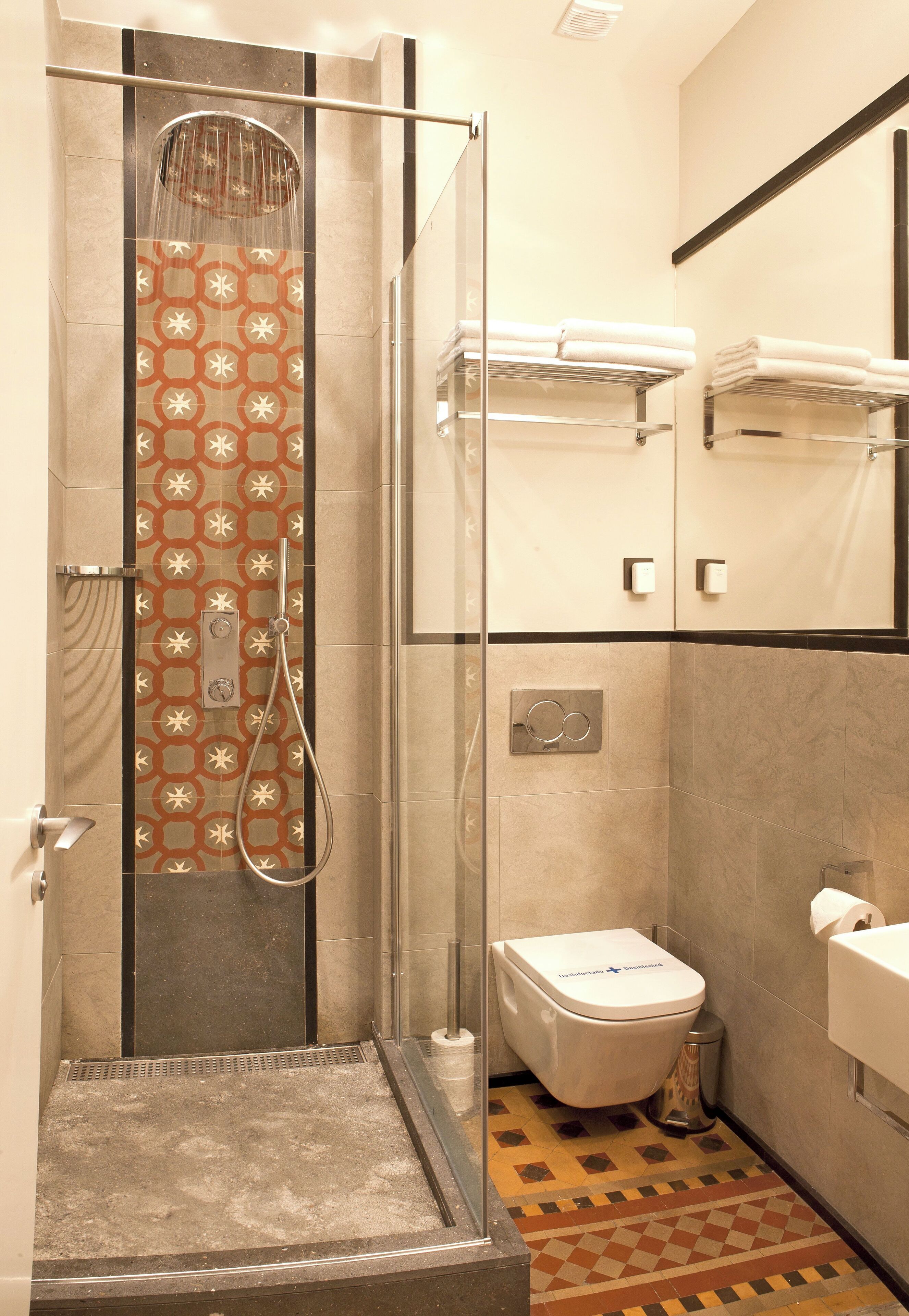 Un baño moderno con ducha, inodoro y toalleros.