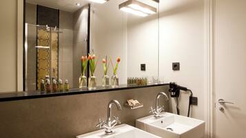 Een moderne badkamer met twee wastafels, een grote spiegel en een haardroger aan de muur.