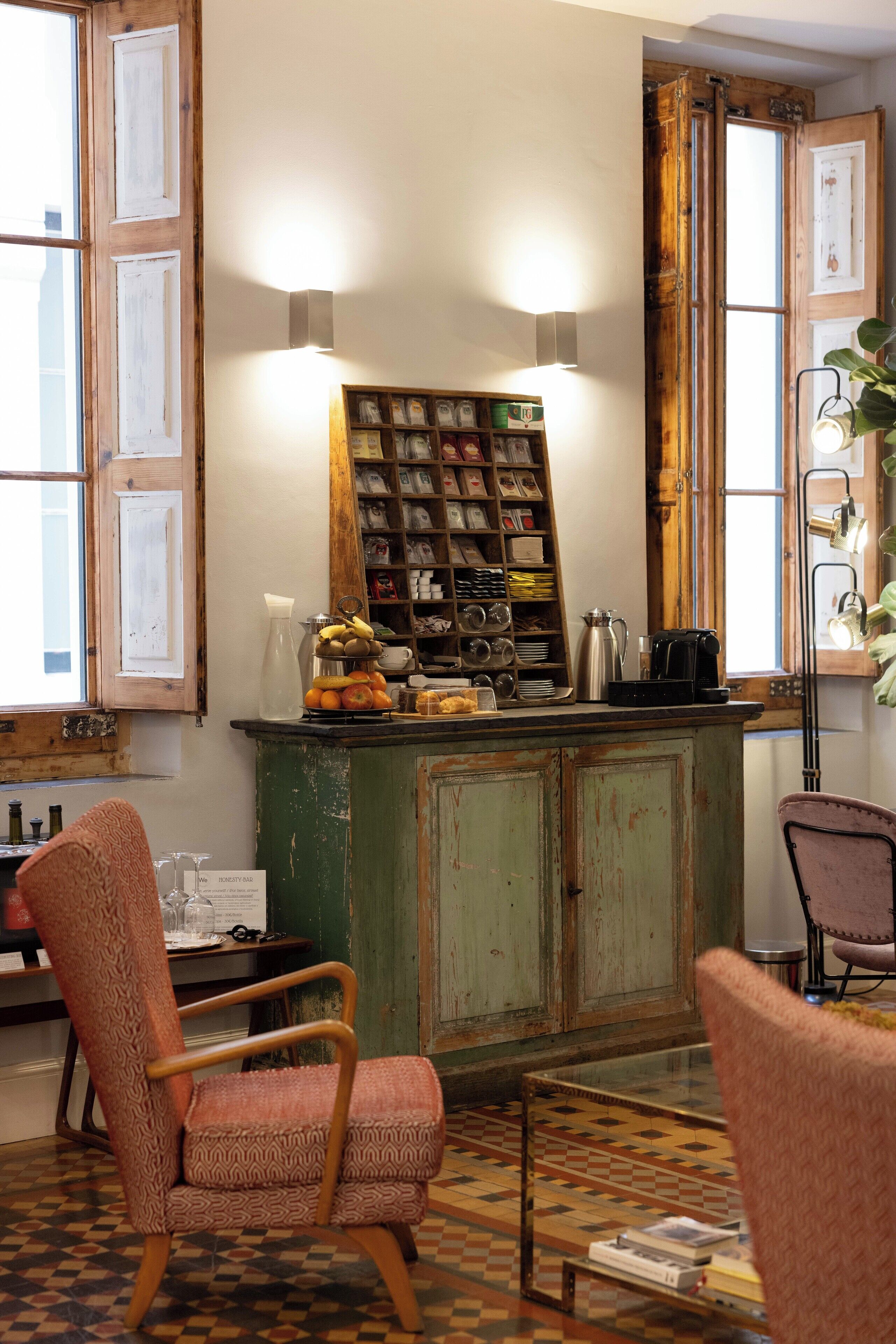 A room with a vintage wooden cabinet, a glass coffee table, and two patterned chairs.