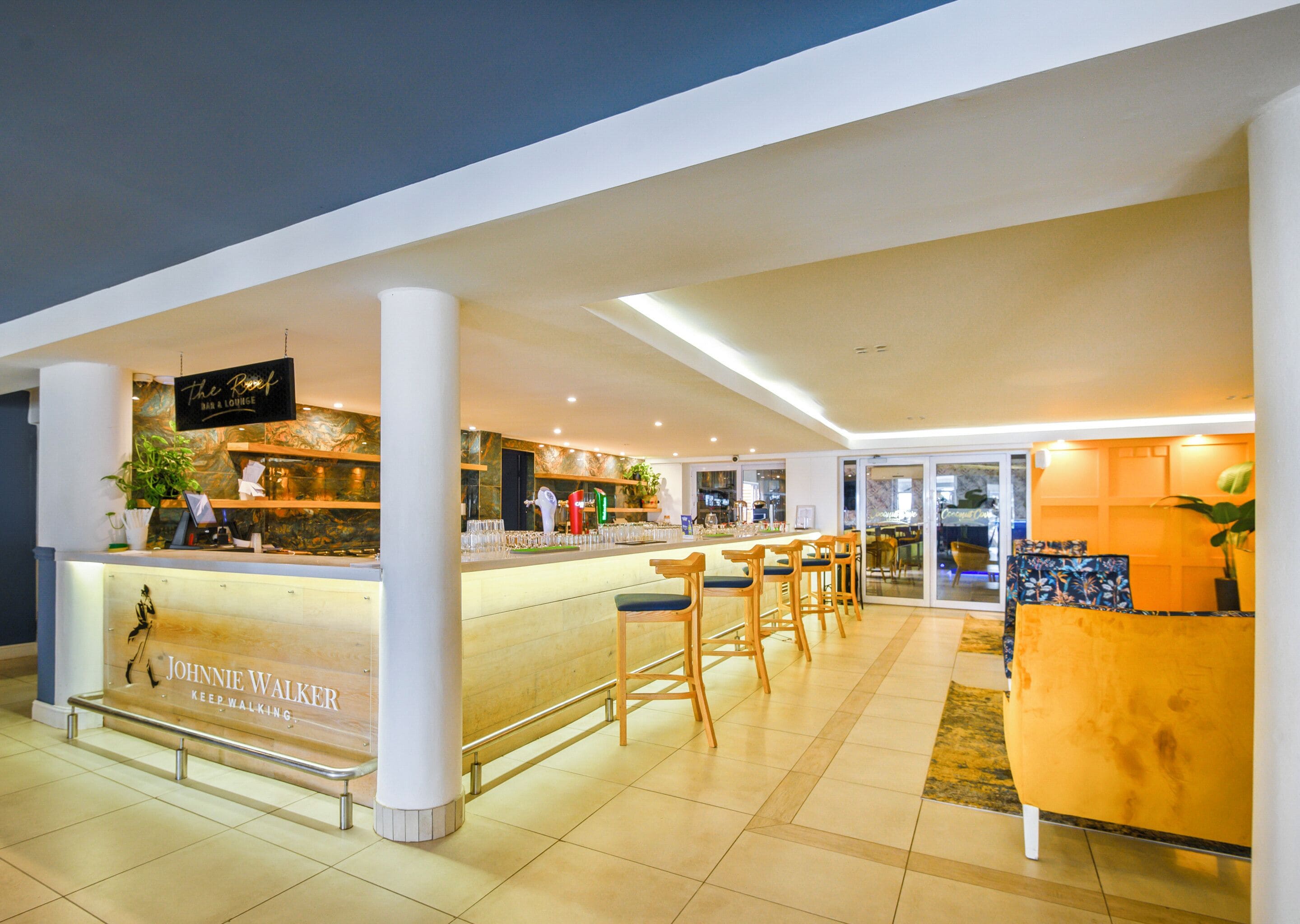 A modern bar area with a counter, stools, and a sign reading "Johnnie Walker."