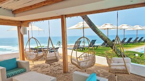 A beachside lounge with wicker furniture, hanging chairs, and umbrellas overlooking the ocean. - Blue Marlin All-Inclusive Seascape by Dream Resorts (Scottburgh)