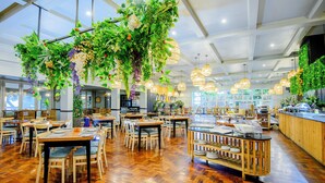 A spacious restaurant with wooden flooring, multiple dining tables, and hanging plants. - Blue Marlin All-Inclusive Seascape by Dream Resorts (Scottburgh)