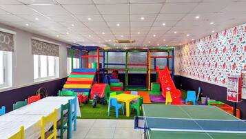 Un área de juegos infantiles con tobogán, red de escalada y mesa de ping pong.