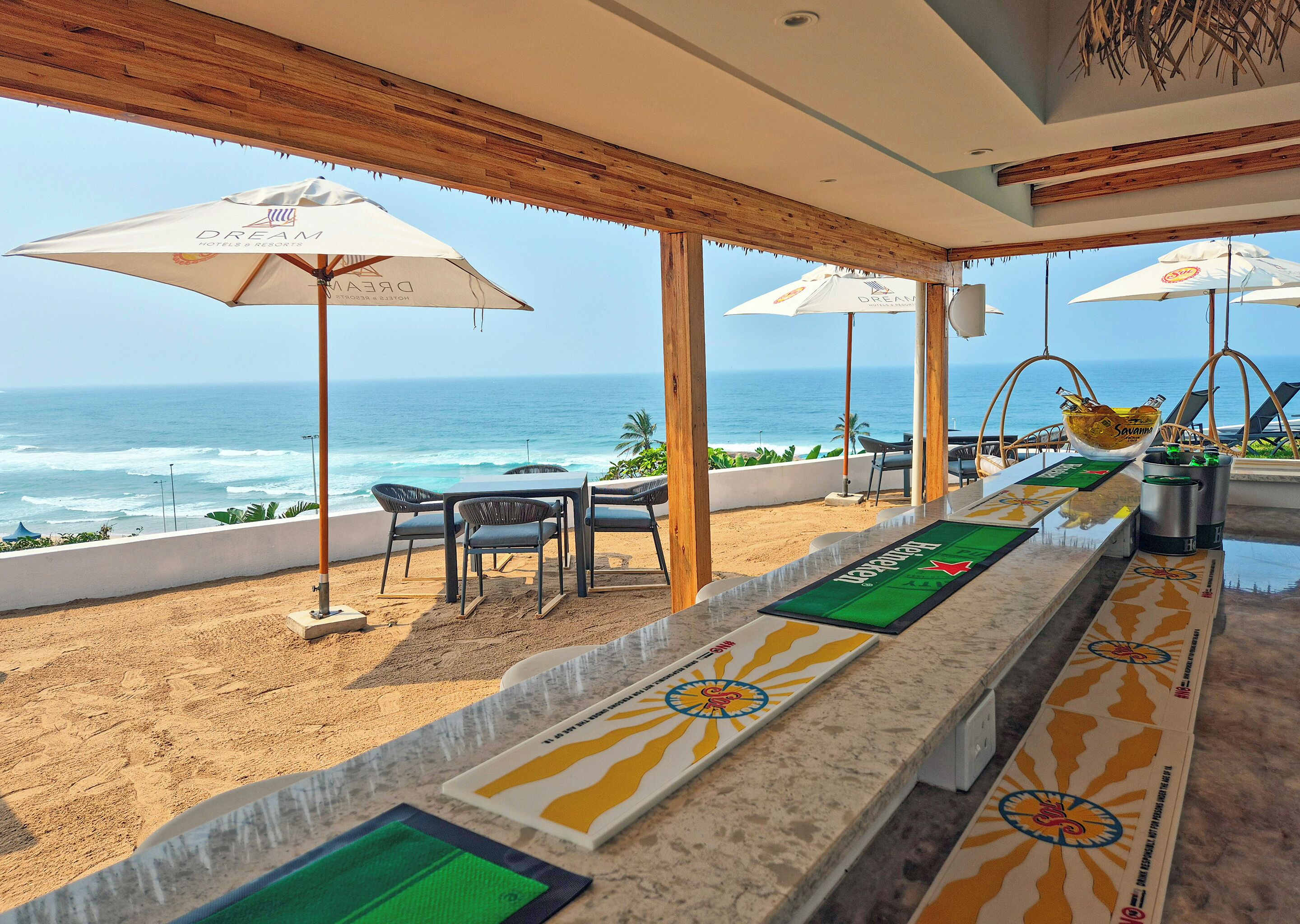 Un bar frente al mar, con vista al océano, techo de madera y sillas de playa.
