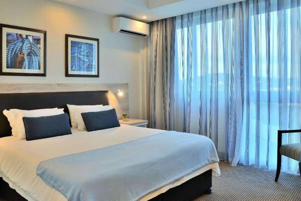 Habitación de hotel con una cama grande, mesitas de noche, una silla y vistas al exterior.