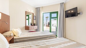 Une chambre d’hôtel avec deux lits, une télévision, un miroir, une commode et une vue sur l’extérieur.
