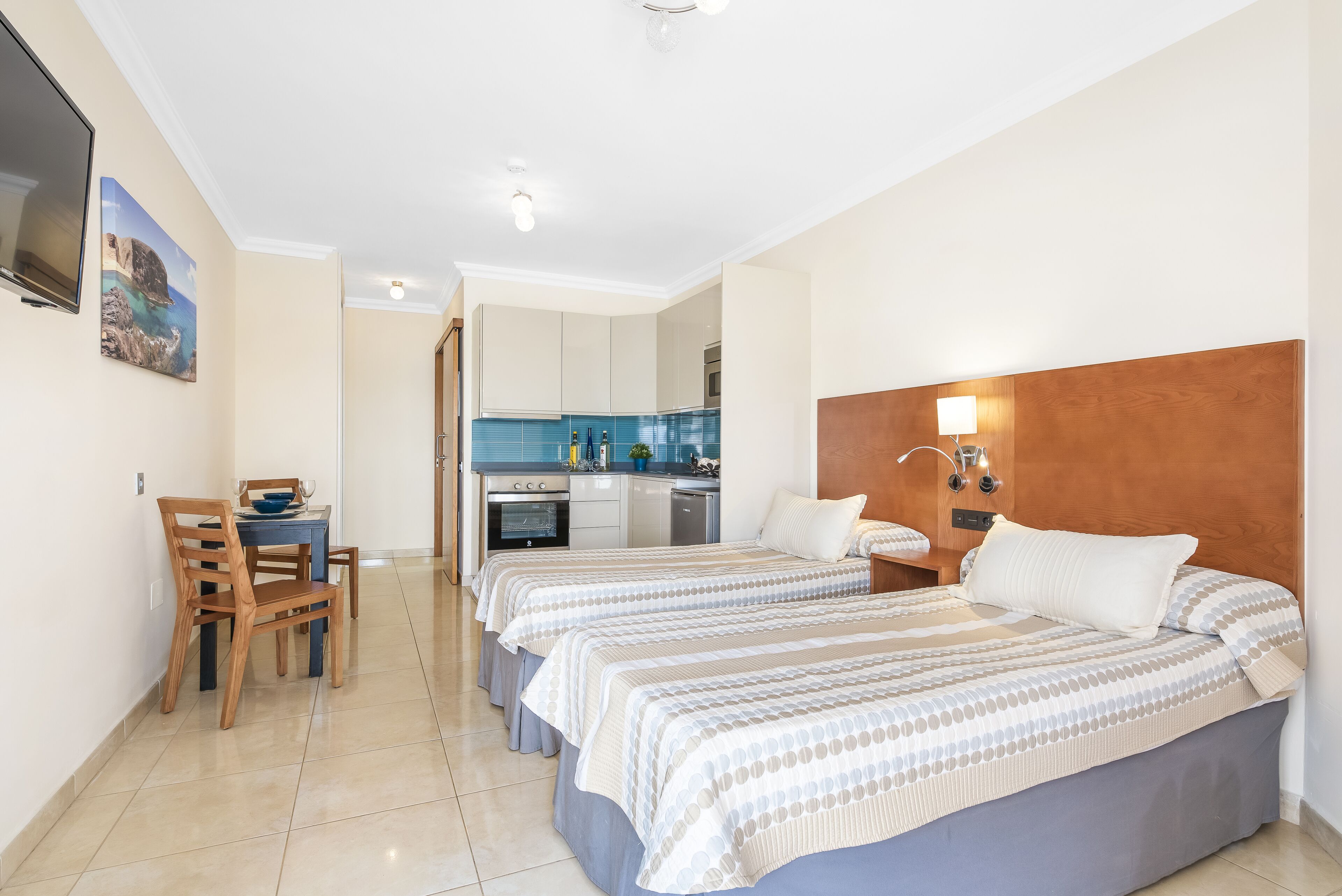 Una camera d'albergo con due letti, un angolo ristoro e angolo cottura.
