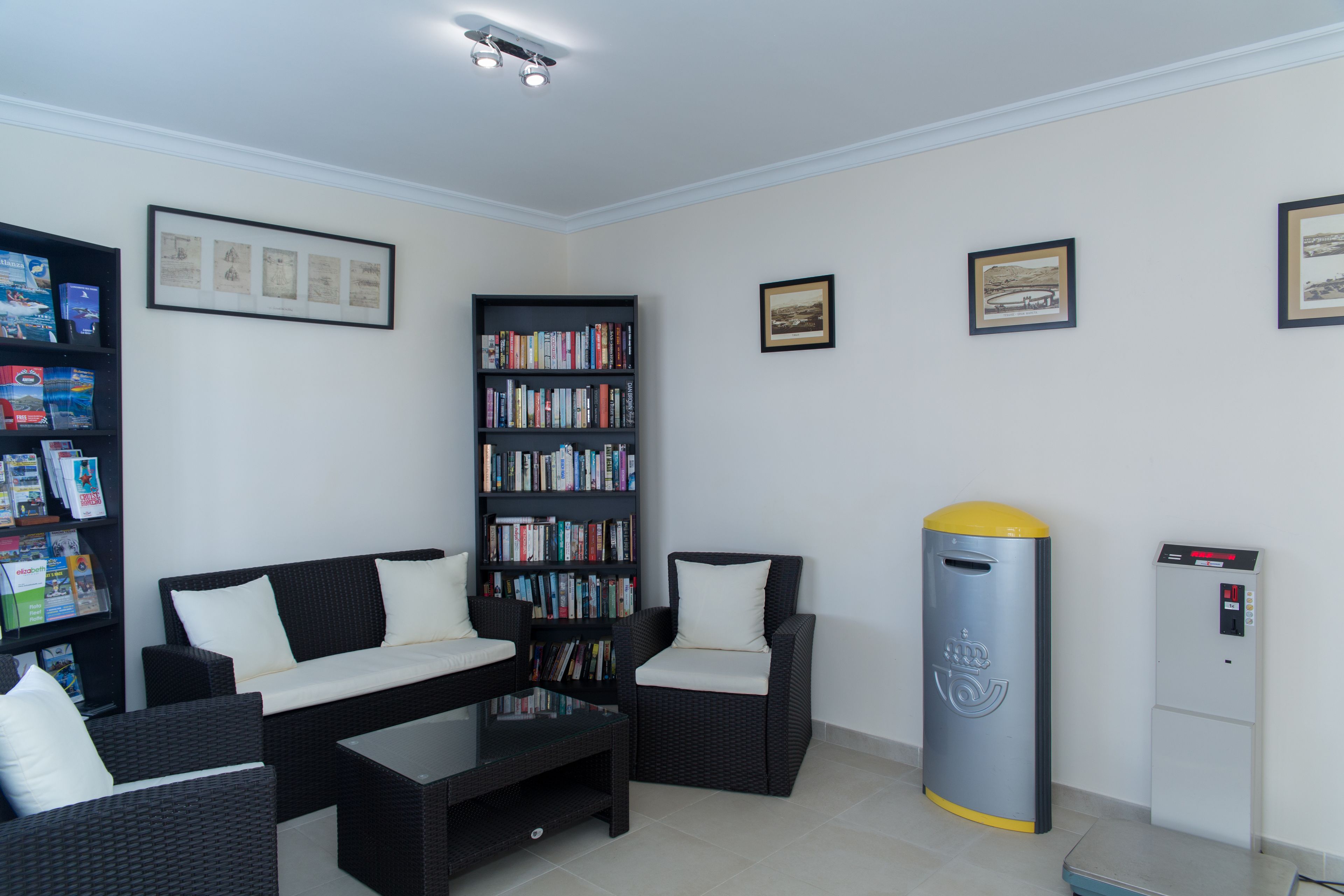 Una sala de estar moderna con un sofá, sillones, una mesa de centro, una estantería y un dispensador de agua.