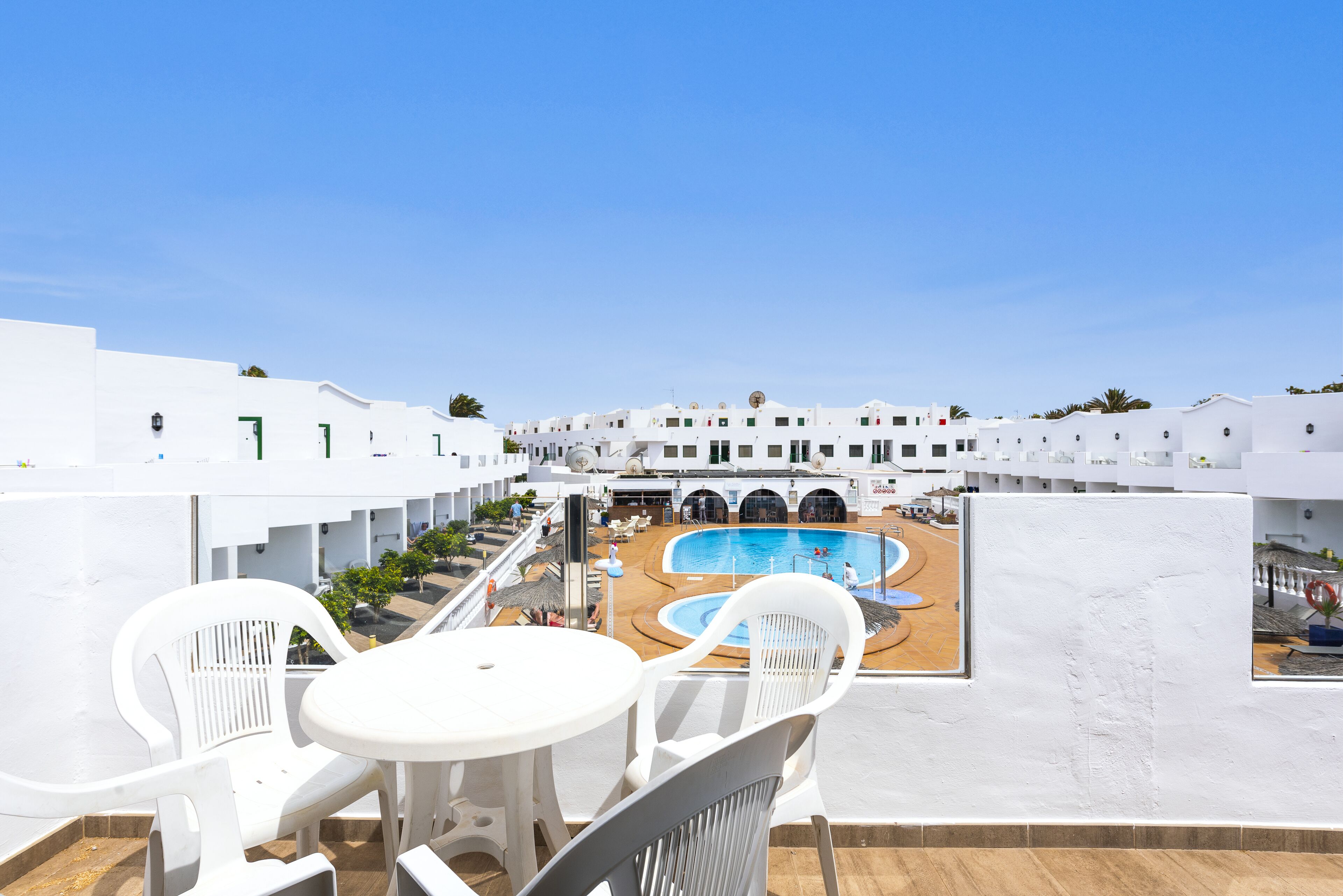 En tagterrasse med hvide vægge, swimmingpool og udendørs møbler.