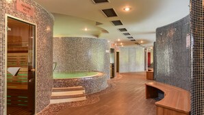 A spa area with a hot tub, wooden benches, and tiled walls. - Hotel Azúr Prémium (Siófok)