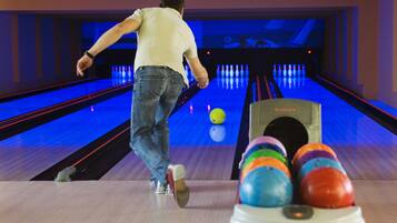 A bowling alley with lanes, a bowling ball, and a ball return machine.