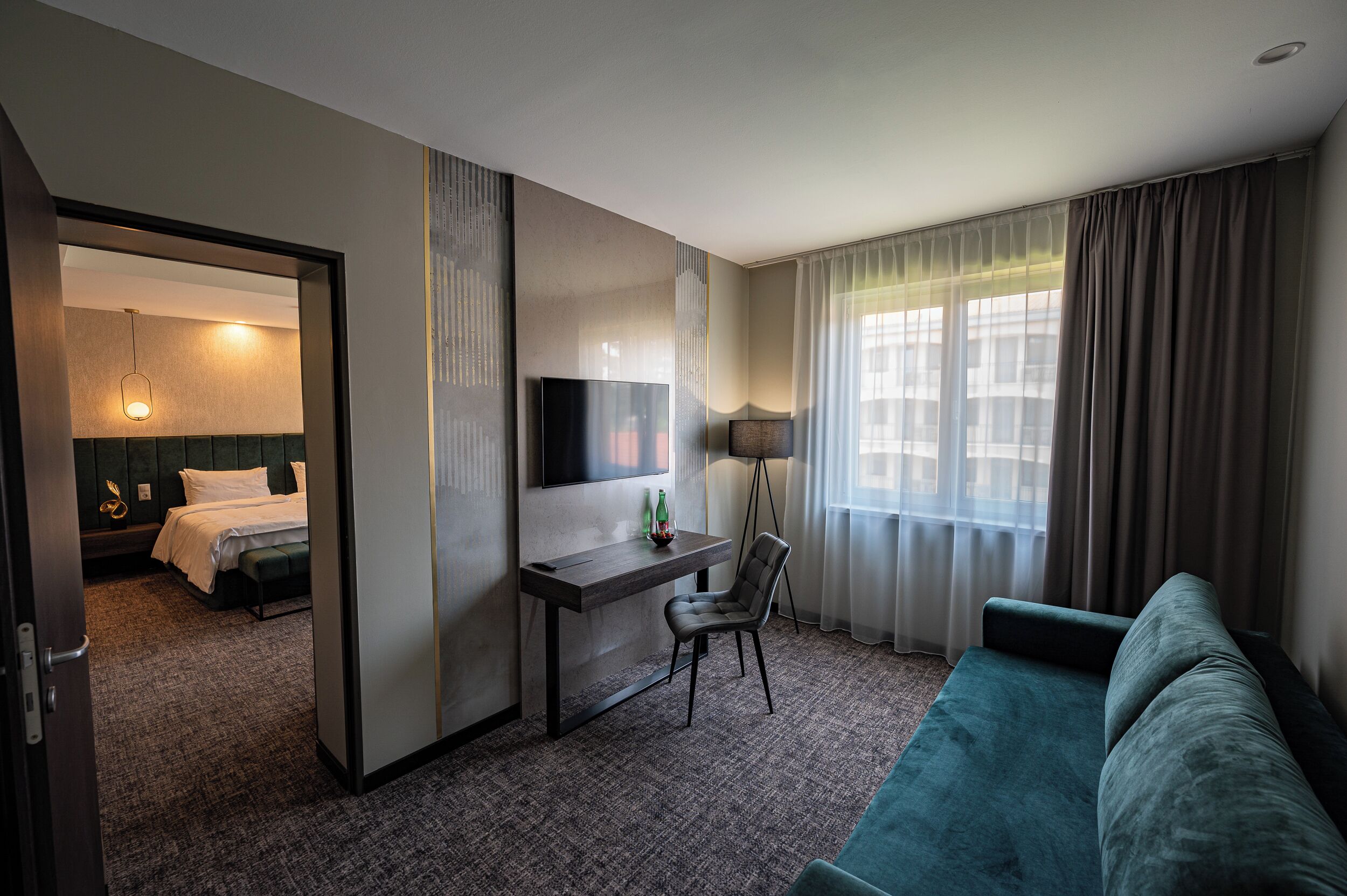 Una habitación de hotel con cama, escritorio, silla, televisión y sofá.