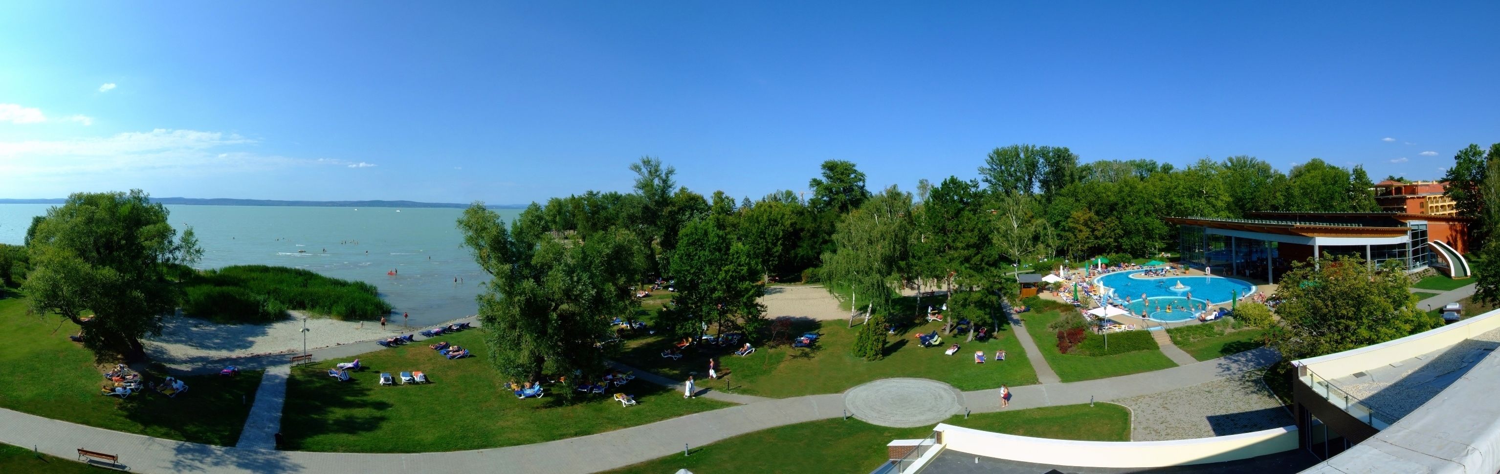 A resort with a large pool, a beach area, and a view of the sea.