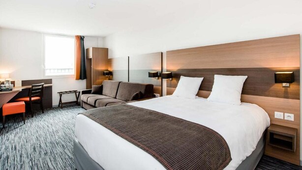 Ein Hotelzimmer mit einem großen Bett, einem Schreibtisch, einem Sessel und einer Couch.