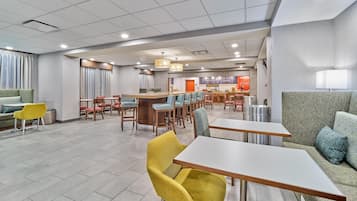 A modern hotel lobby with a bar area, seating arrangements, and a visible counter.