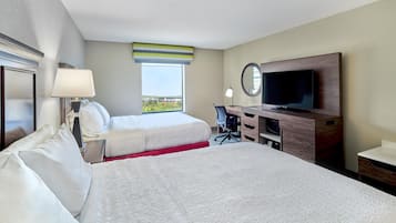A hotel room with a large bed, a smaller bed, a desk, a TV, and a window with a view.