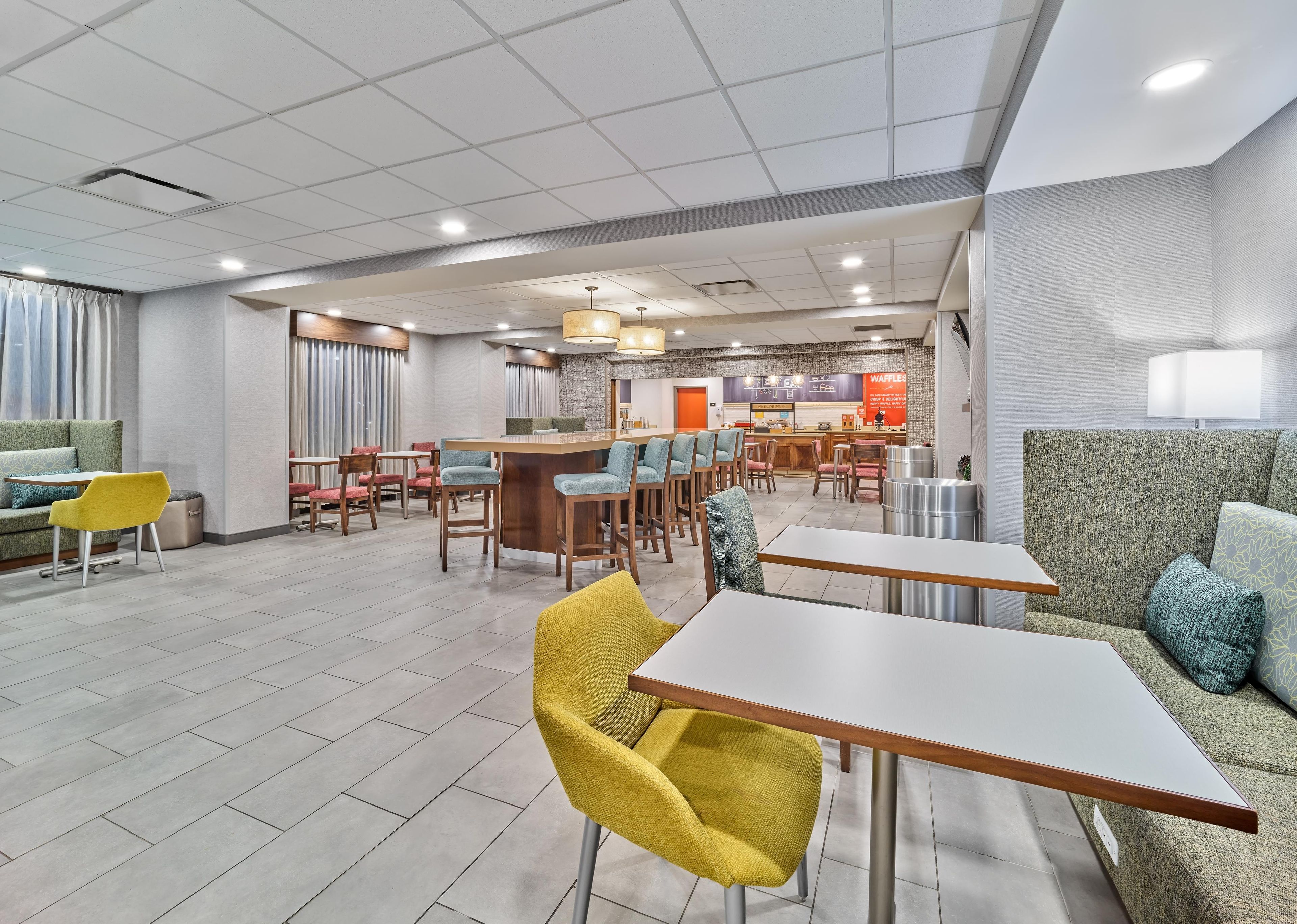 A modern hotel lobby with a bar area, seating arrangements, and a visible counter.