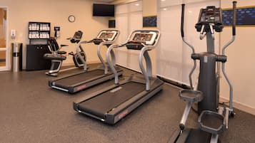 Ein Fitnessstudio mit Laufbändern, einem Ergometer und einer Gewichtbank.