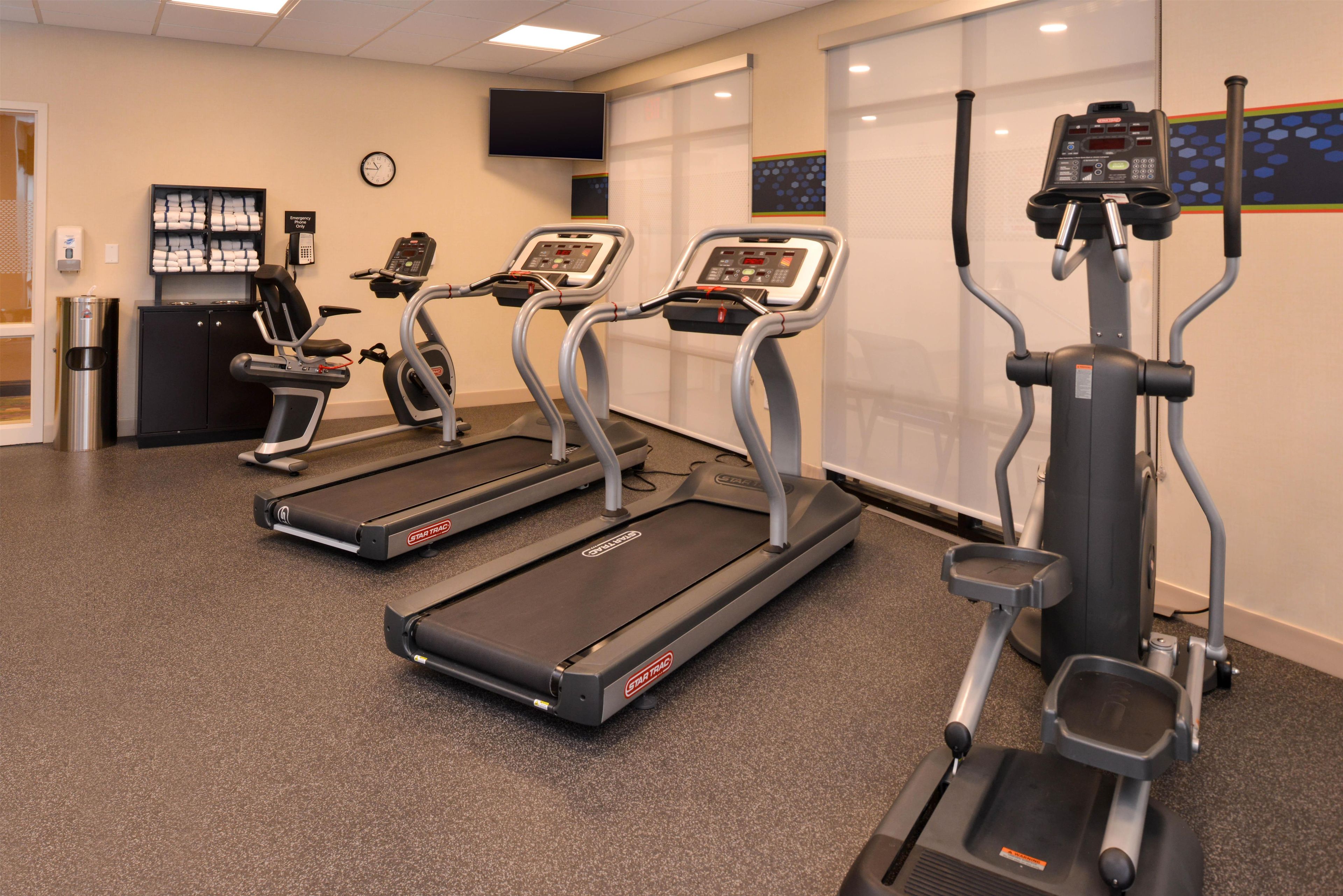 A fitness center with treadmills, a water dispenser, and a clock on the wall.