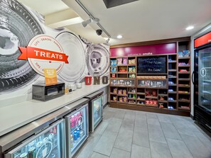 A self-service beverage station with a sign for treats, a digital screen, and a refrigerator stocked with beverages. - Hampton Inn Omaha Midtown-Aksarben Area (Omaha)