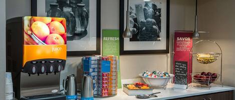 A juice dispenser, coffee maker, and various food containers on a counter.