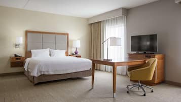 A hotel room with a bed, bedside tables, a desk, a chair, a television, and curtains.