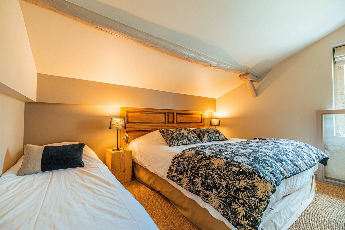 A bedroom with two beds, wooden headboards, and bedside lamps.