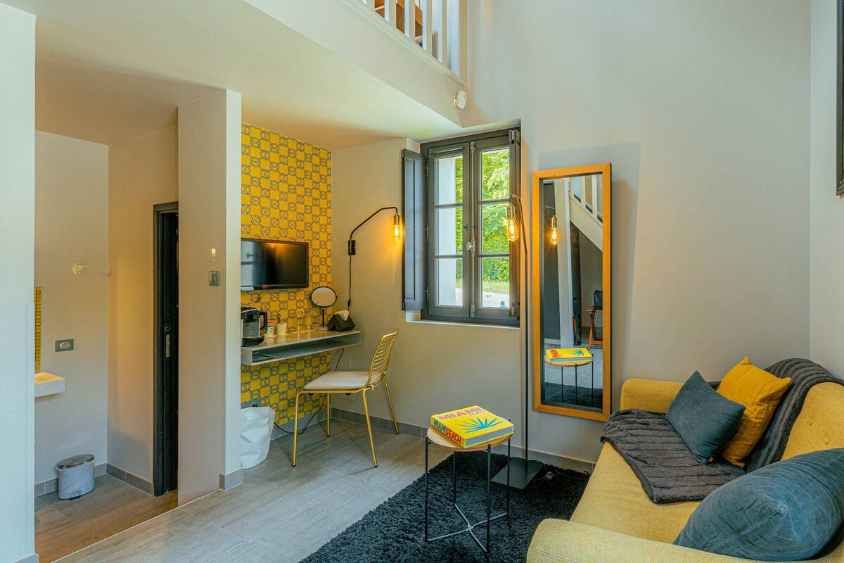 A compact living space with a kitchenette, a dining area, and a seating area with a sofa and a chair.