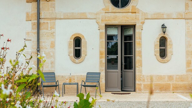A building with a stone facade, a large arched doorway, and two small windows. - Clos Marcamps (Prignac-et-Marcamps)