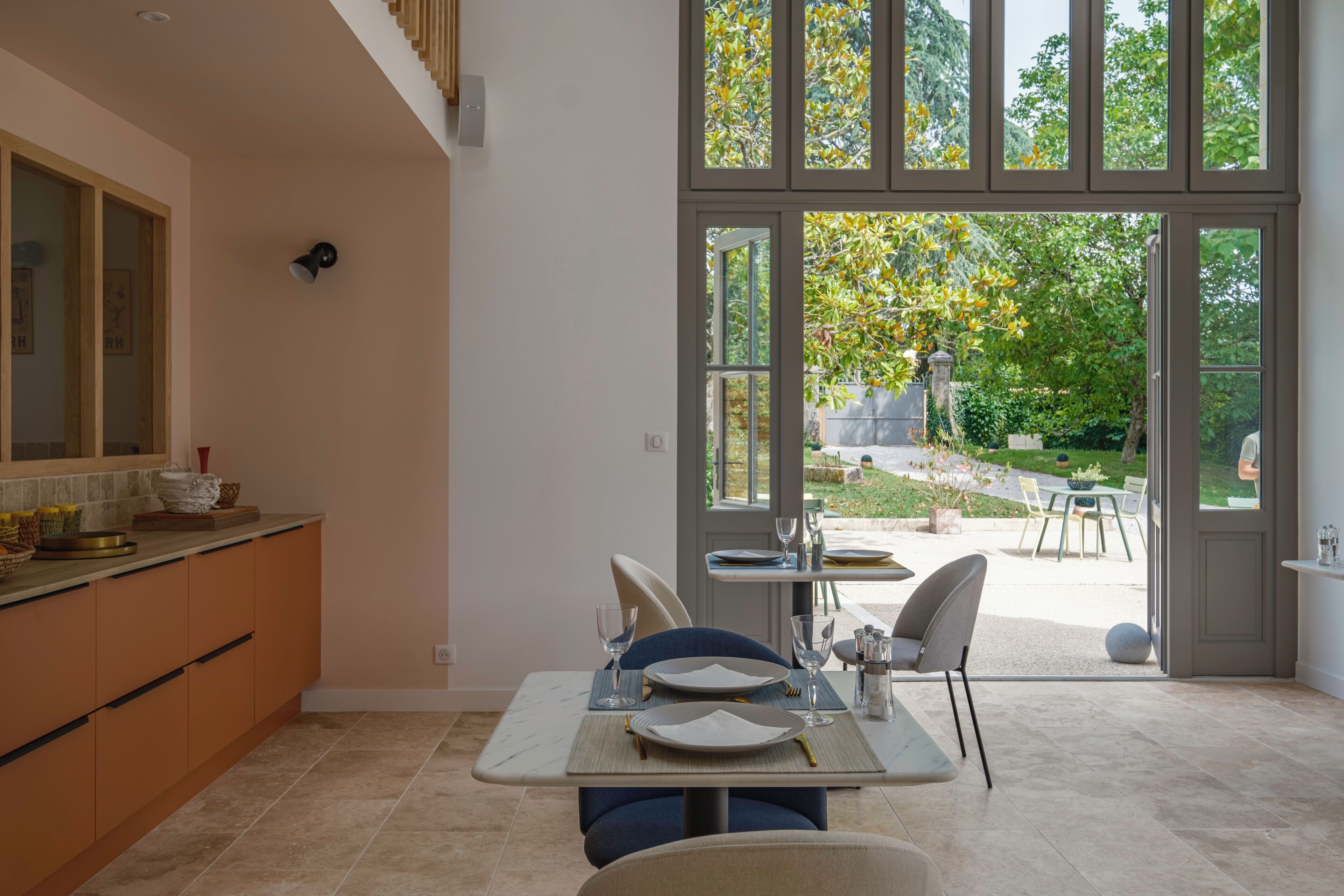 Une cuisine moderne avec un coin repas, de grandes fenêtres et une vue sur le jardin.