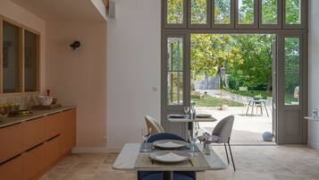 Une cuisine moderne avec un coin repas, de grandes fenêtres et une vue sur le jardin.