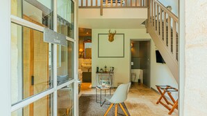 A spacious living area with a high ceiling, a staircase, and a dining area with a table and chairs. - Clos Marcamps (Prignac-et-Marcamps)