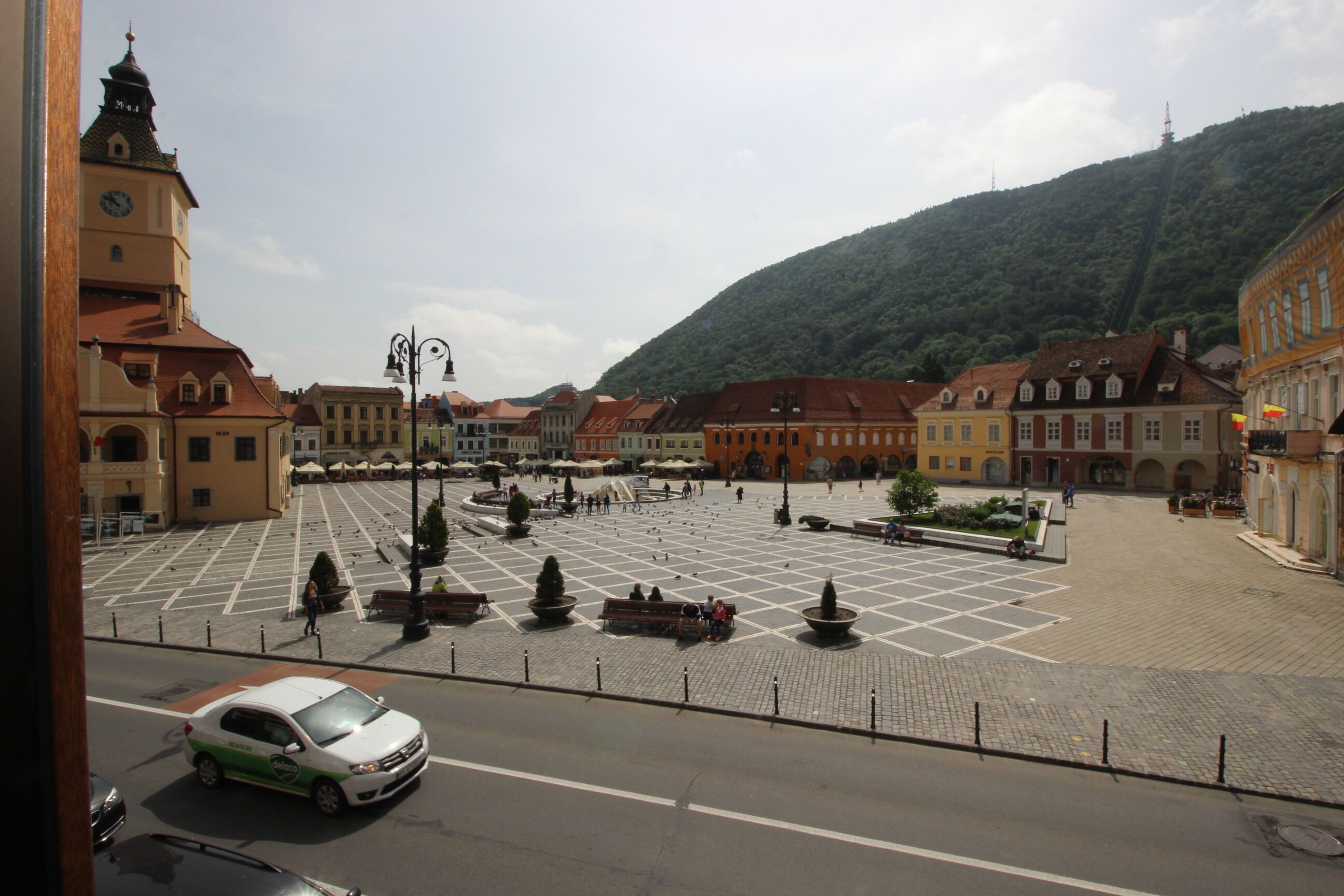 Una plaza con una fuente central, rodeada de edificios históricos y una iglesia con campanario.
