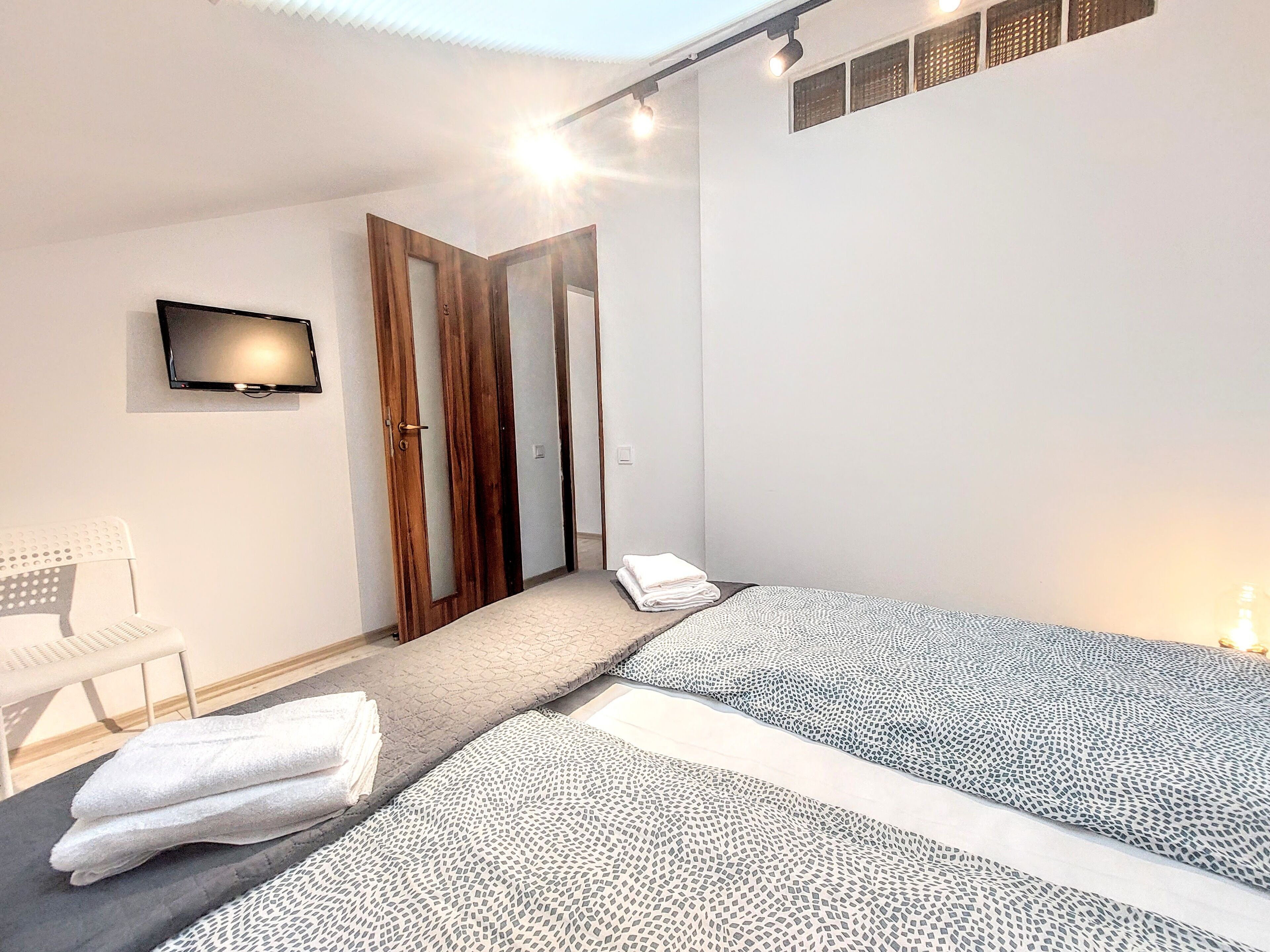 Een moderne slaapkamer met twee bedden, een televisie en een stoel.