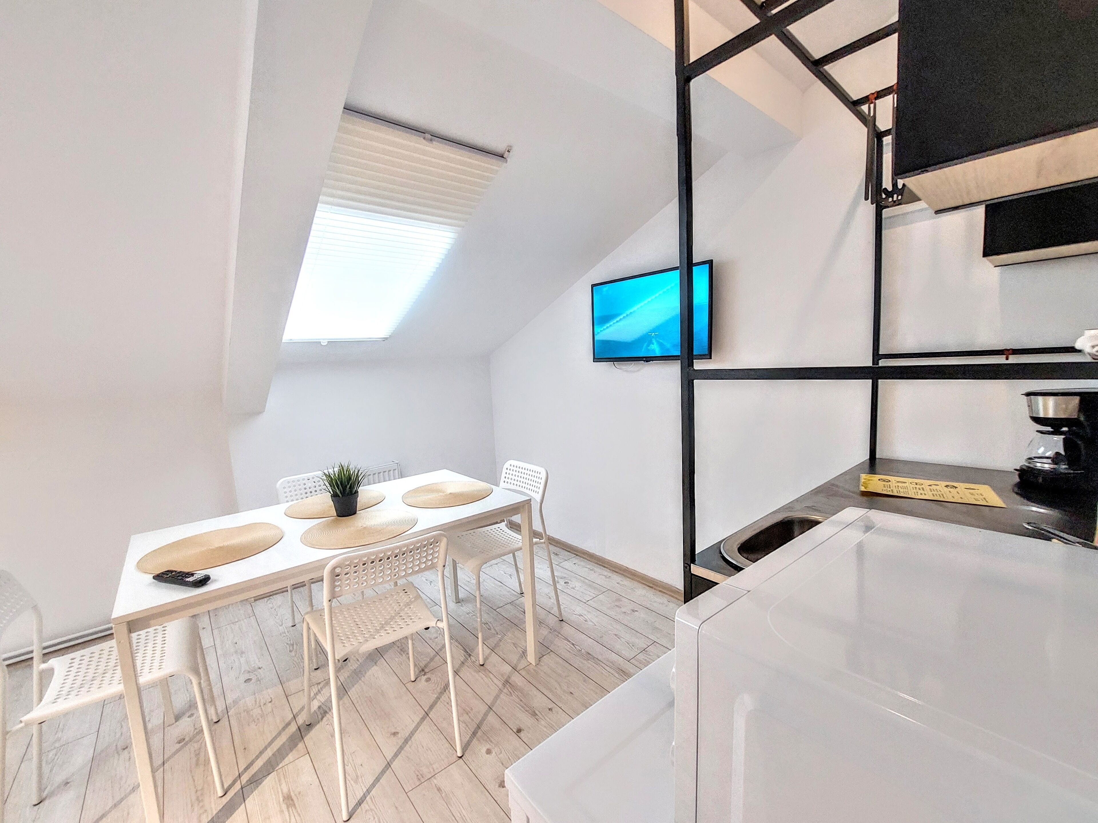 Een moderne keuken met een inbouwoven, een koffieapparaat en een klein eethoekje met een tafel en stoelen.