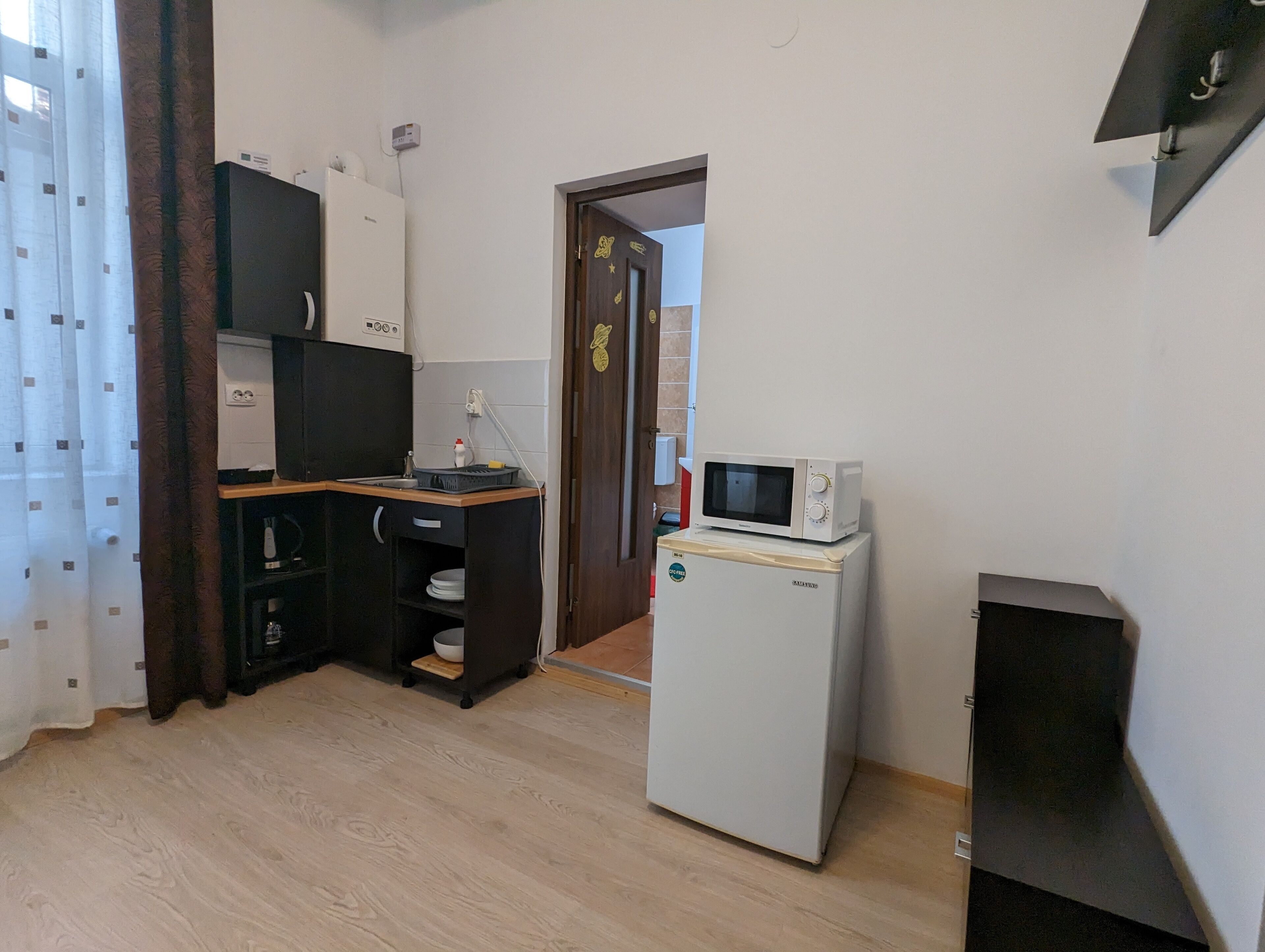 Una cocina compacta con microondas, refrigerador y una pequeña encimera.