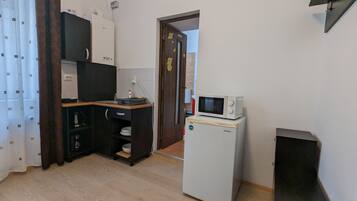 Una cocina compacta con microondas, refrigerador y una pequeña encimera.