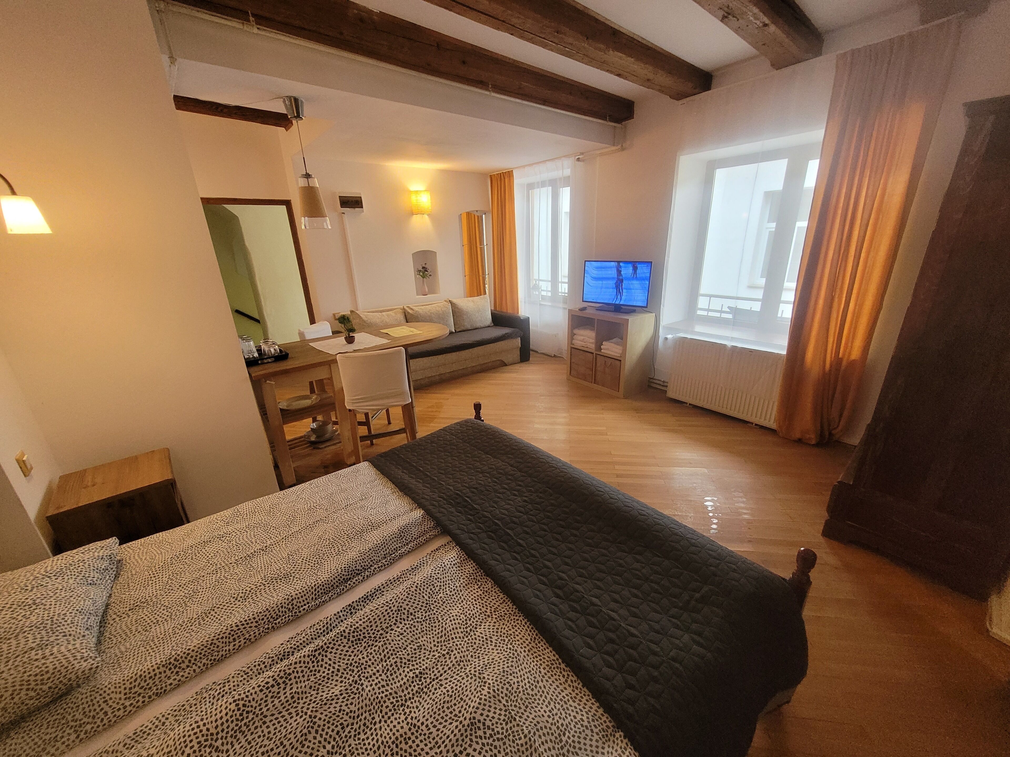 Una habitación acogedora con cama, escritorio, silla, televisión y ventana con cortinas.