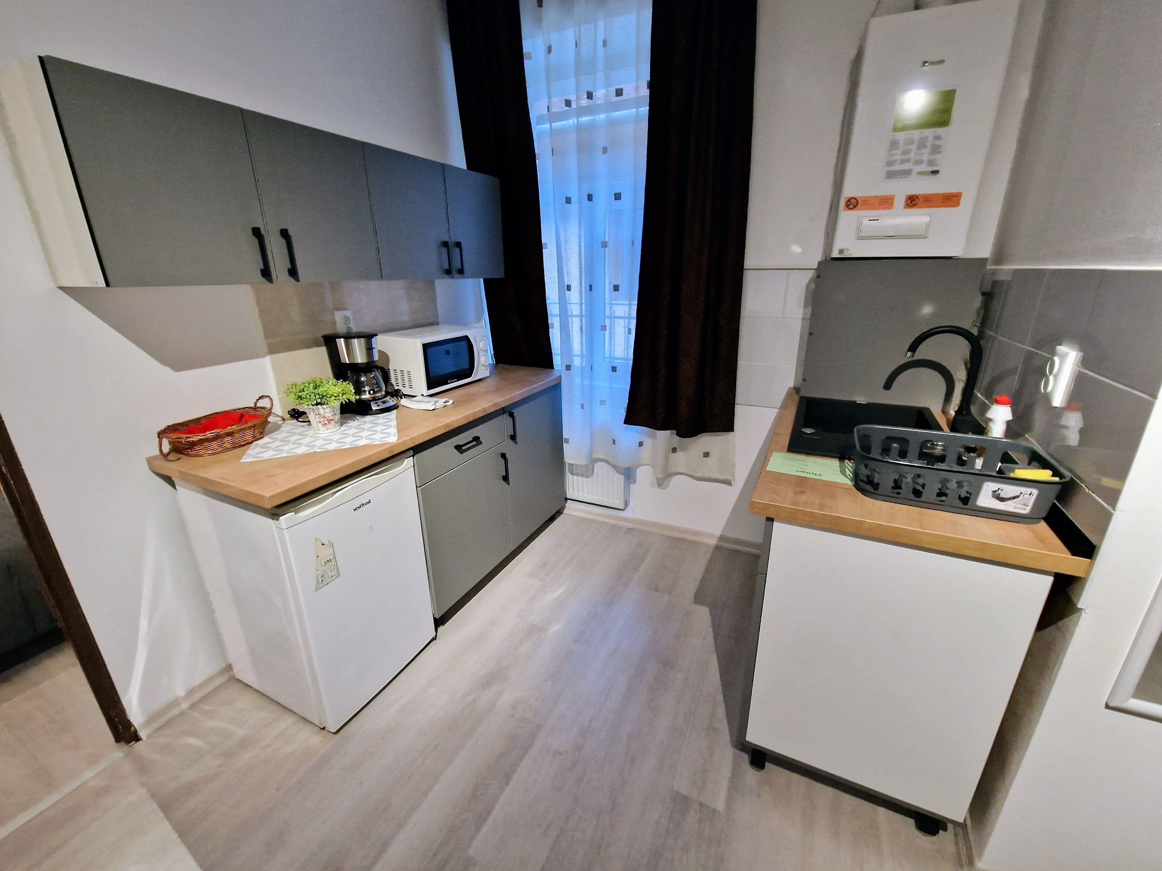 Una cocina compacta equipada con microondas, cafetera y refrigerador pequeño.