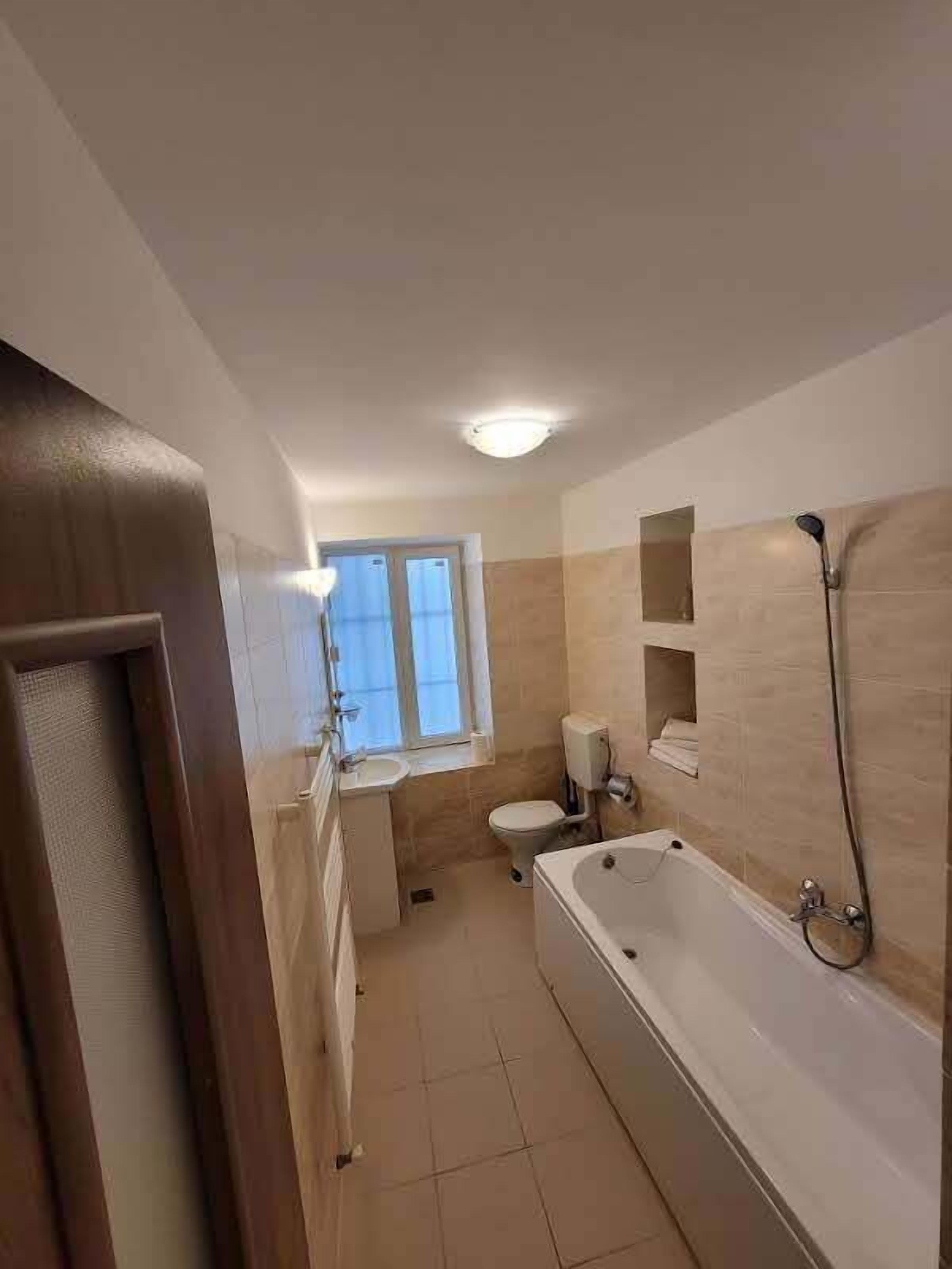 Un baño con bañera, inodoro, lavabo y ventana.