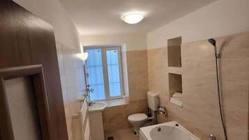 Un baño con bañera, inodoro, lavabo y ventana.