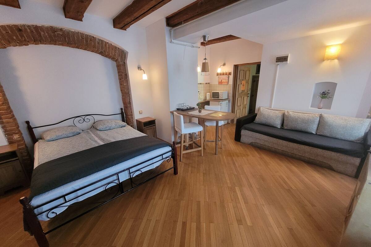 A bedroom with a bed, a sofa, a desk, and a chair.