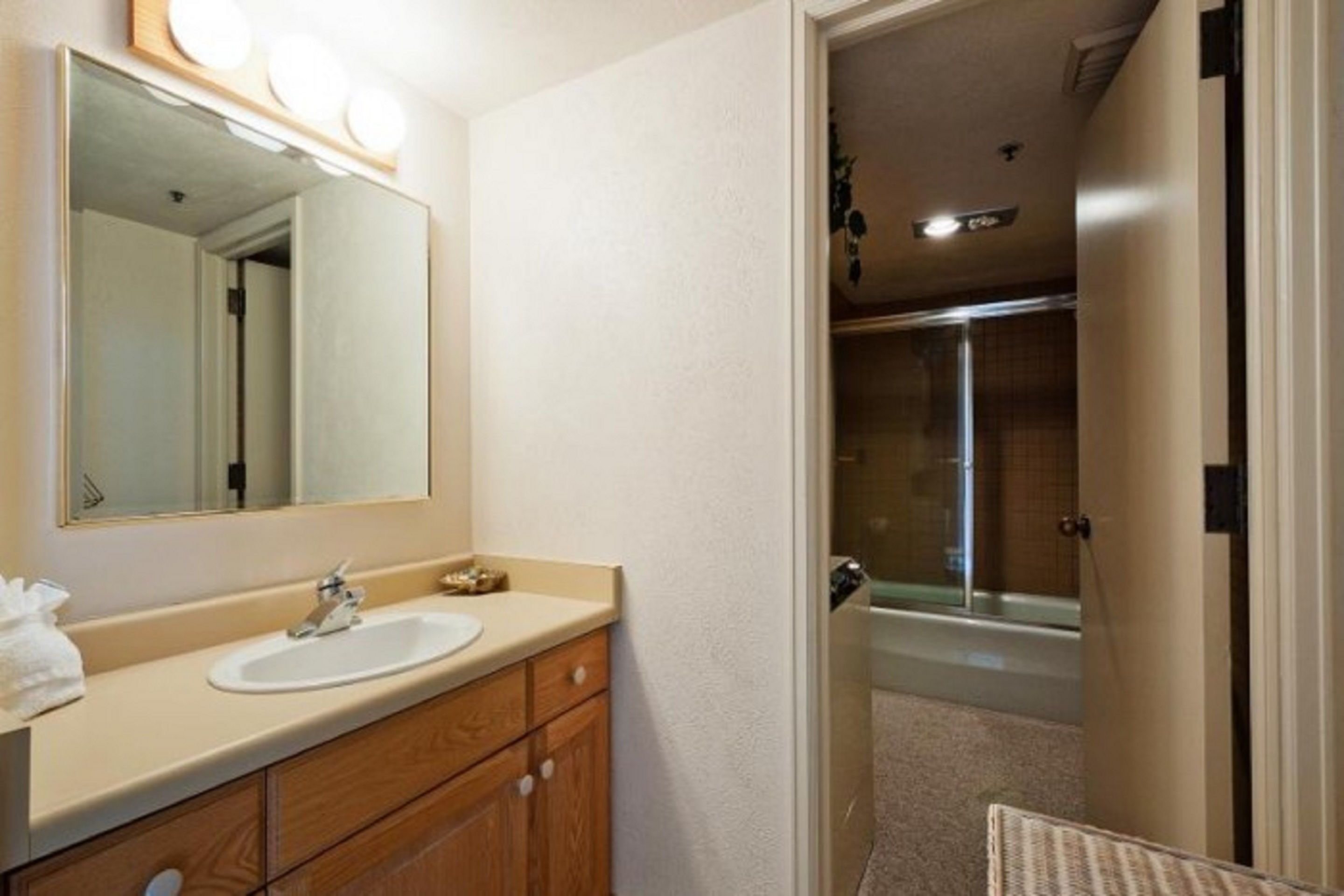 A bathroom with a sink, mirror, and shower.